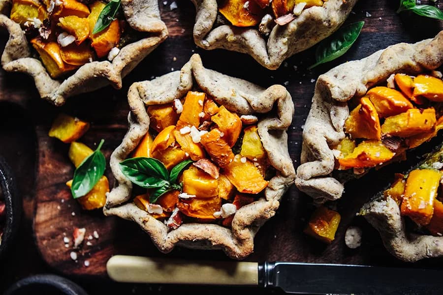 Rustic squash galettes with fresh basil on a dark wooden board